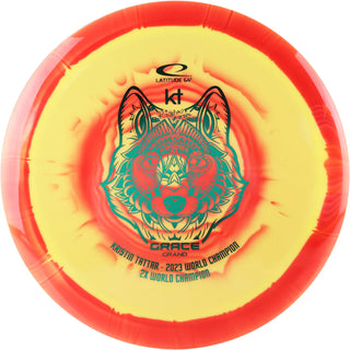 A yellow and red Grand Orbit Grace disc golf disc.