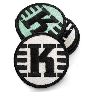 White and mint-colored textile patches with the Kastaplast logo on them.