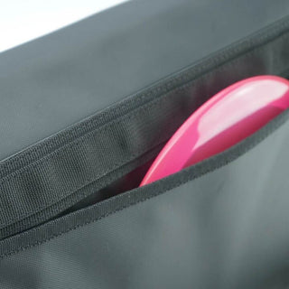 A close up view of a disc golf shoulder bag containing one pink disc in the side pocket.